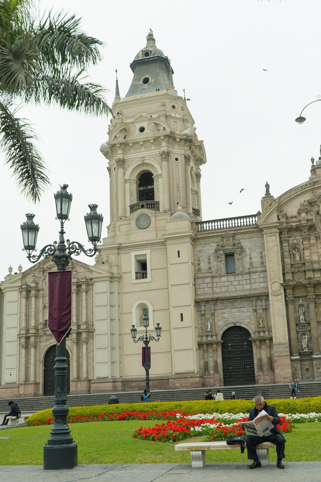 Elderly Chilean man reading a newspaper on a park bench in a city plaza